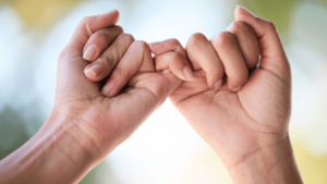 zwei Hände, eingehakte kleine Finger von Freunden zur Unterstützung
