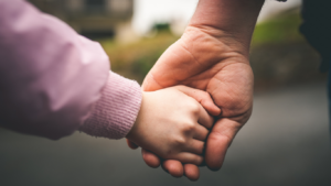 Kind und Erwachsene halten sich an der Hand