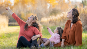 auf einer Wiese sitzen Großmutter, Mutter und Kind