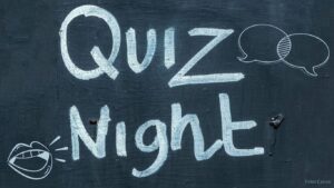 Tafel auf der Quiz Night steht, daneben Sprechblasen und ein Mund der spricht