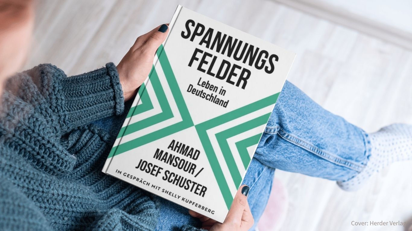 Jemand hält das Buch: Spannungsfelder Leben in Deutschland von Ahmad Mansour und Josef Schuster in der Hand (Cover Weiß mit grünen dreiecken)